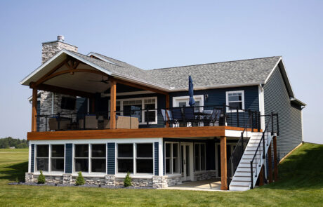 exterior of blue house with large balcony deck with sunroom below