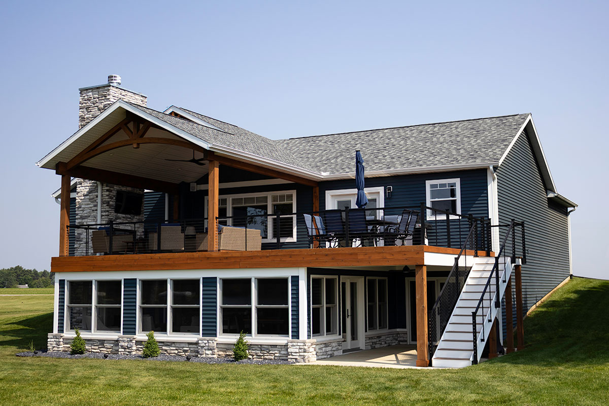exterior of blue house with large balcony deck with sunroom below
